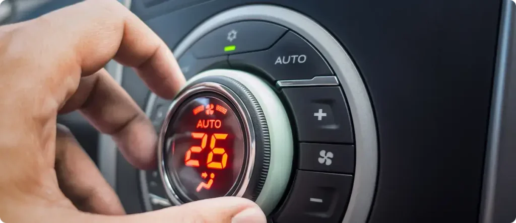Driver adjusting the car’s climate control system to 26 degrees using the automatic air conditioning temperature dial on the dashboard.
